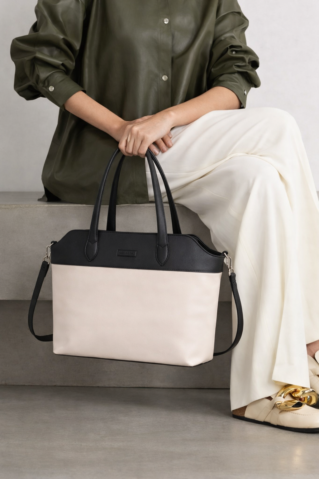 woman carrying off white and black leather tote bag