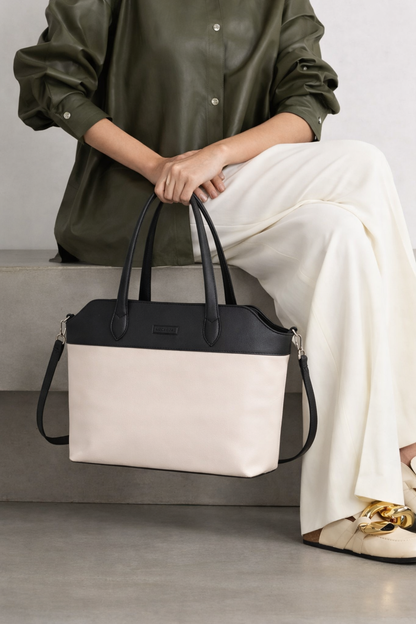 woman carrying off white and black leather tote bag